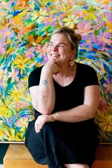 Pia Kuykhoven in front of one of her floral paintings